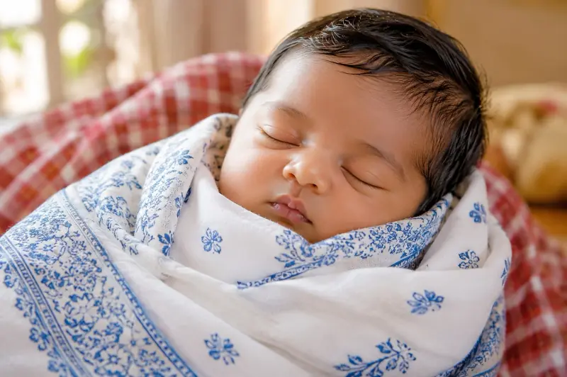 Sleeping newborn wrapped in a patterned blanket